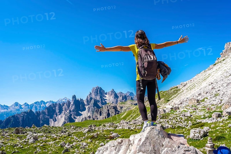 Hiker with open arms enjoying the breathtaking view of the tre cime di lavaredo, a symbol of the dolomites, embracing the freedom of nature during a summer day