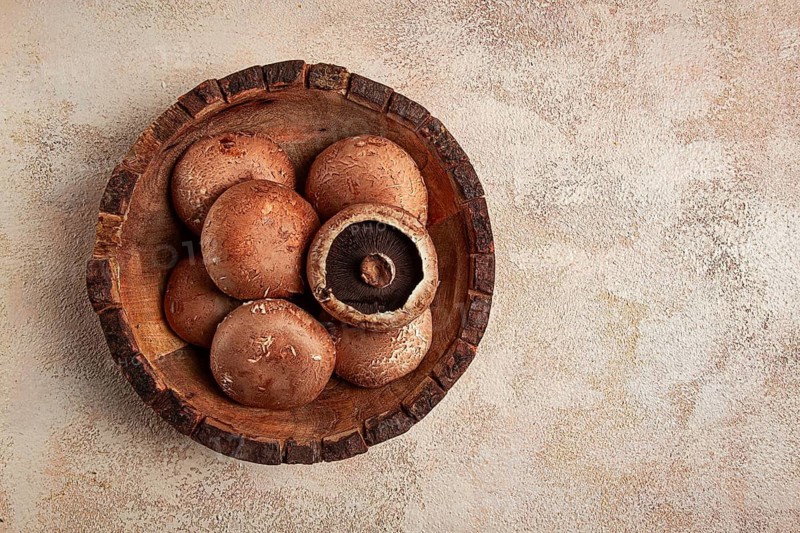 Fresh Portobello mushrooms, in a wooden bowl, top view, close-up, no people