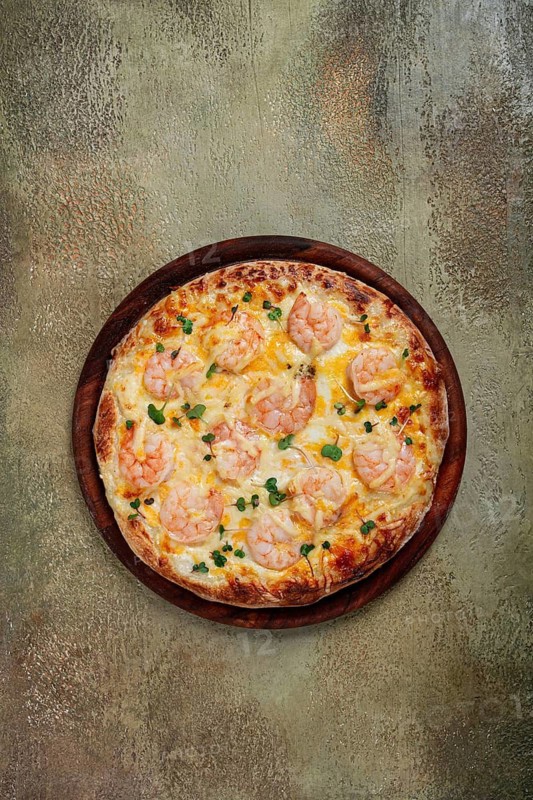 Four cheese pizza with shrimp and fresh microgreens, served on a wooden board, homemade, no people