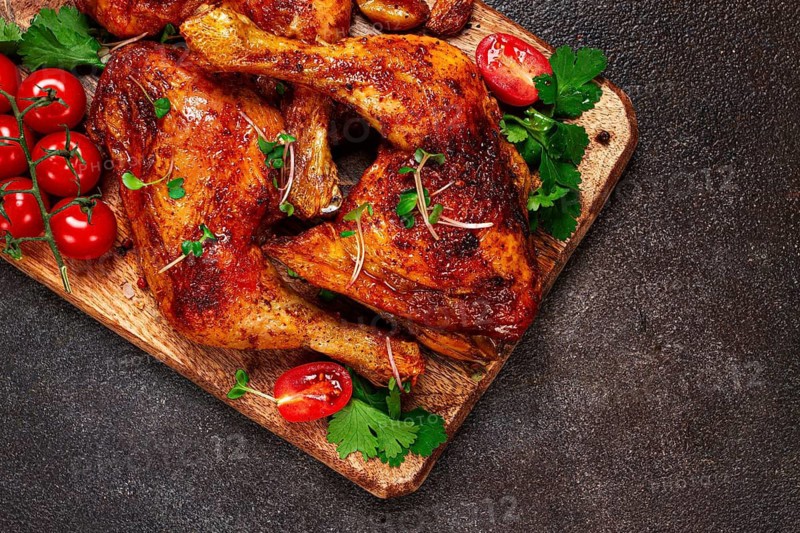 Grilled fried chicken legs, served with fresh cherry tomatoes, and herbs, on a wooden chopping board, homemade, no people