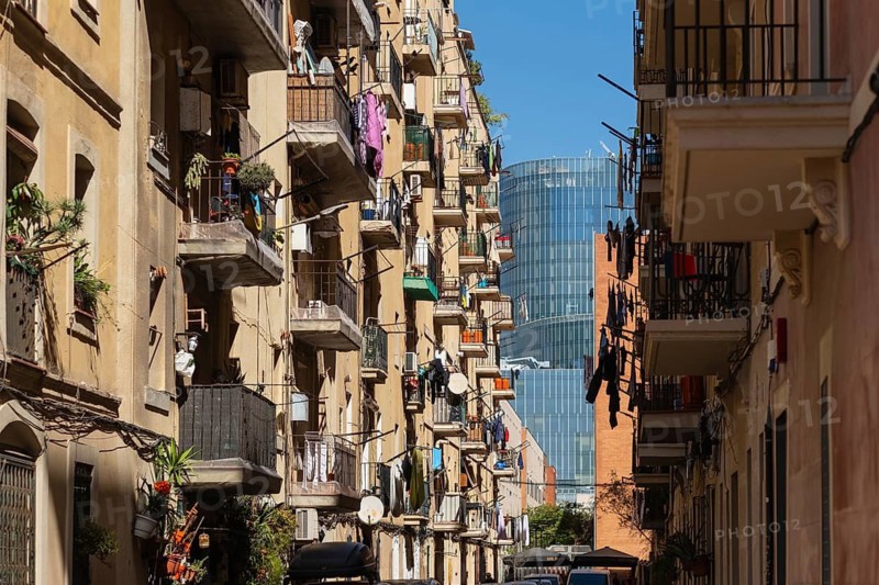 Narrow alley of houses in the Barceloneta neighbourhood, in the background modern skyscrapers in Barcelona, Spain