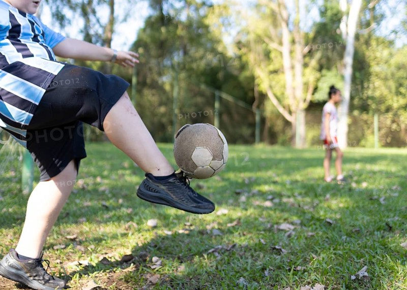 Cropped unrecognizable Brazilian children play soccer on a lush grass field in Tres Coroas, Brazil. The scene captures joy and movement, reflecting local culture and youthful energy