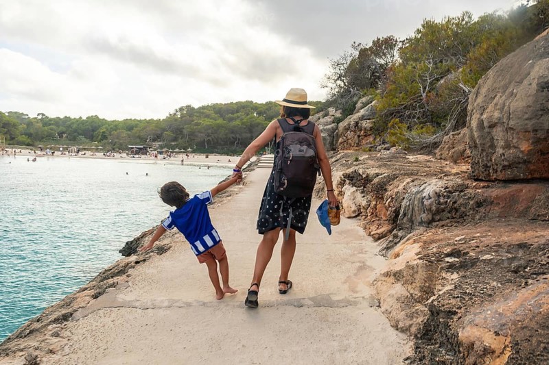 Mother and son enjoying summer holidays, walking along the scenic coast of s'amarador beach in mallorca, spain