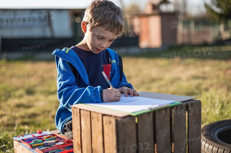 Little boy writing and learning in the garden bicouse school is closed due to Covid-19 pandemic in Tymowa, Poland