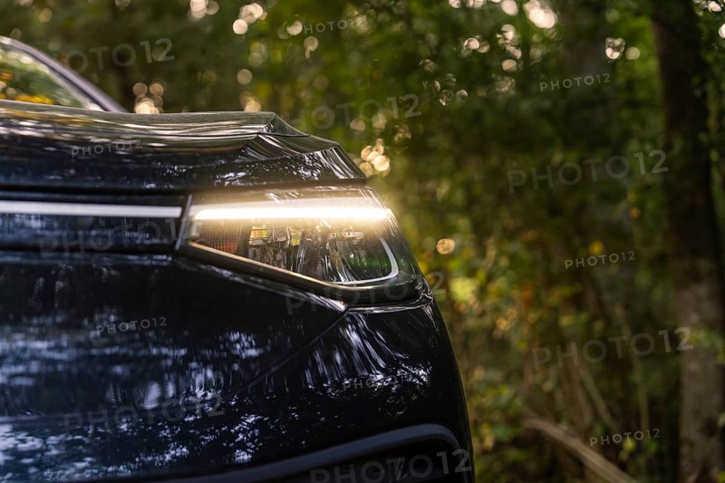Close-up of the headlight of a car in the forest, reflecting light, natural environment, electric car, VW ID5, Gechingen, Black Forest, Germany