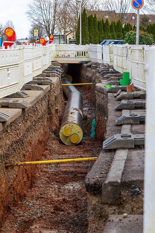 Construction trench with installed district heating pipes and barriers in an urban area