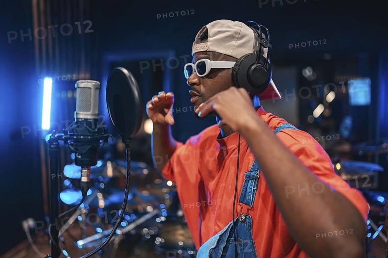 Talented musician wearing headphones and stylish sunglasses, singing passionately into a microphone in a modern recording studio, creating new music