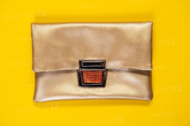 Golden faux leather clutch against a plain yellow background