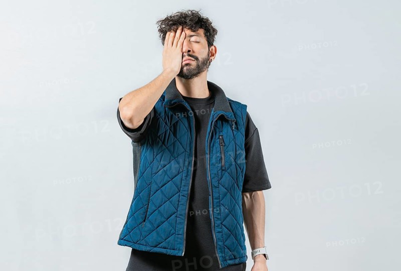 Tired and exhausted person covering his face with the palm of his hand. Exhausted young man putting the palm on his face