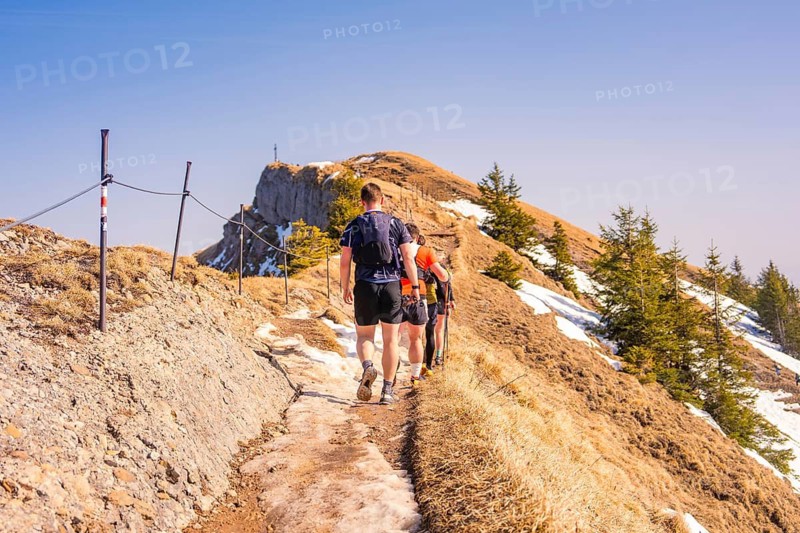People hiking on a snowy mountain trail in sunny weather, Hochgrat Mountains, Allgäu Alps, Oberreute, Germany