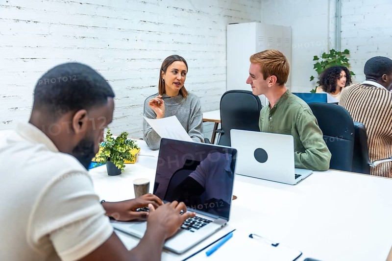 Multiracial people working using laptop in a modern coworking space with shared tables
