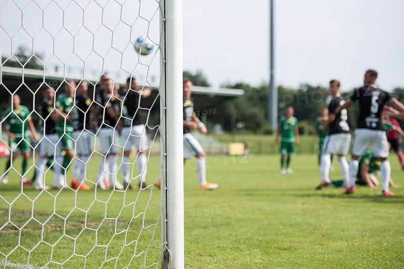 Detail of goal's post with net and football players during free kick in the background in Lubin, Poland