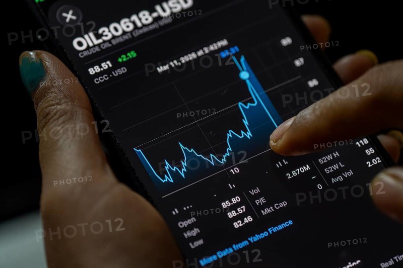 In this photo illustration, a person looks at a smartphone displaying Brent crude oil prices in USD, in Guwahati, India, on March 11, 2026. Oil prices reversed course from recent highs, slipping to around 90 USD a barrel after remarks by U.S. President Donald Trump on the Iran conflict. Markets remain unsettled as traders monitor the evolving geopolitical situation