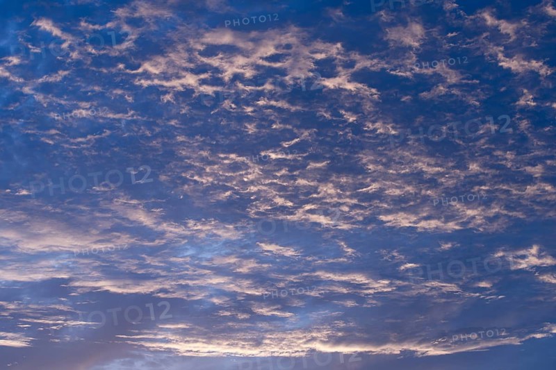 A serene evening sky filled with soft, wispy clouds illuminated by gentle twilight hues. The sky transitions from blue to soft purple, creating a peaceful atmosphere