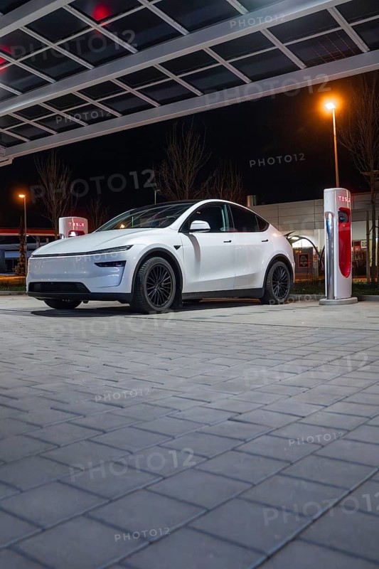 White electric car at a charging station under a covered area at night, Tesla, Leonberg, Germany