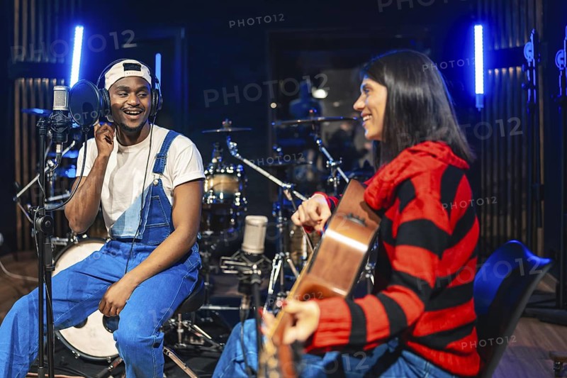 Two musicians playing guitar and singing, recording a new hit song in a professional recording studio