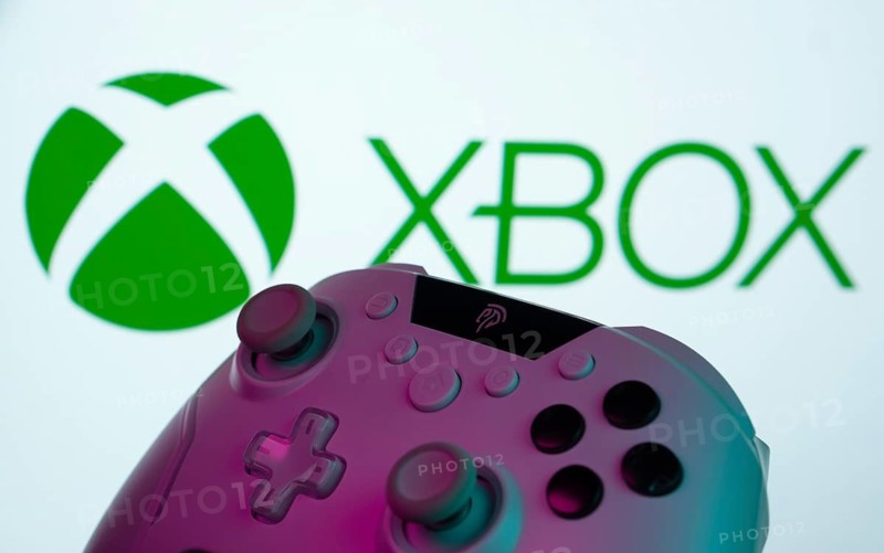 Dhaka, Bangladesh- 09 May 2025: A close-up of a white gamepad with the XBOX seen on screen in the background