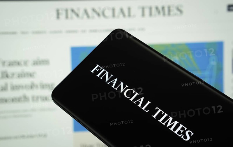 The logo of the newspaper Financial times is displayed on a smartphone screen, and the website Financial times is visible on a computer screen in the background