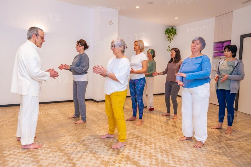 Qi gong instructor and women closing eyes and breathing during a indoor class