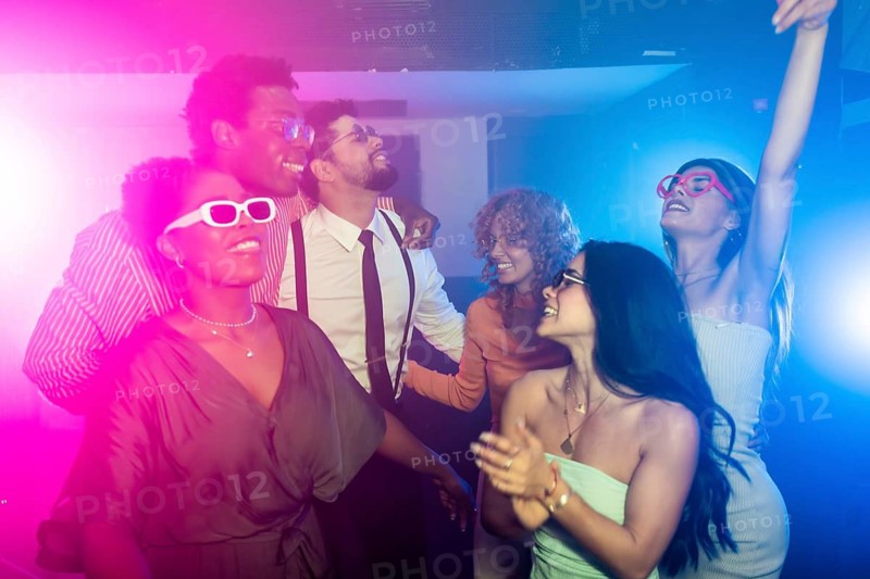 Happy multi ethnic friends dancing joyfully together at a vibrant disco party, surrounded by colorful lights and an energetic atmosphere