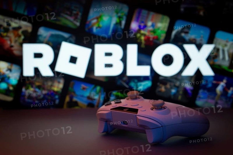 Dhaka, Bangladesh- 26 July 2025: A close-up of a white gamepad with The Roblox seen on screen in the background