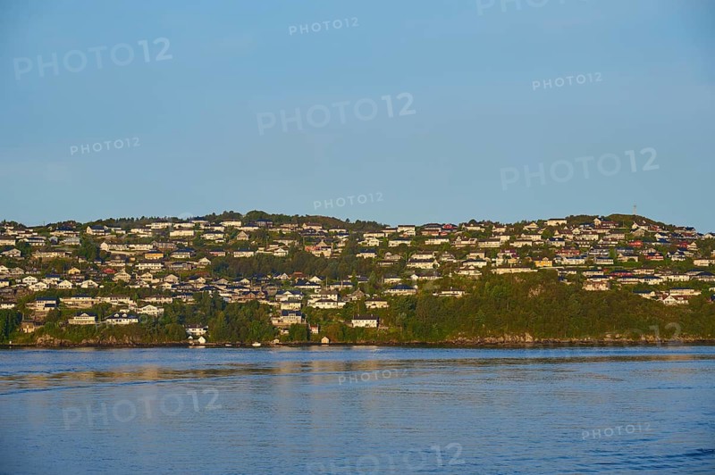 Small wooded island with houses in the sea with clear skies and calm water, Strusshamn, Bergen, Vestland, Norway
