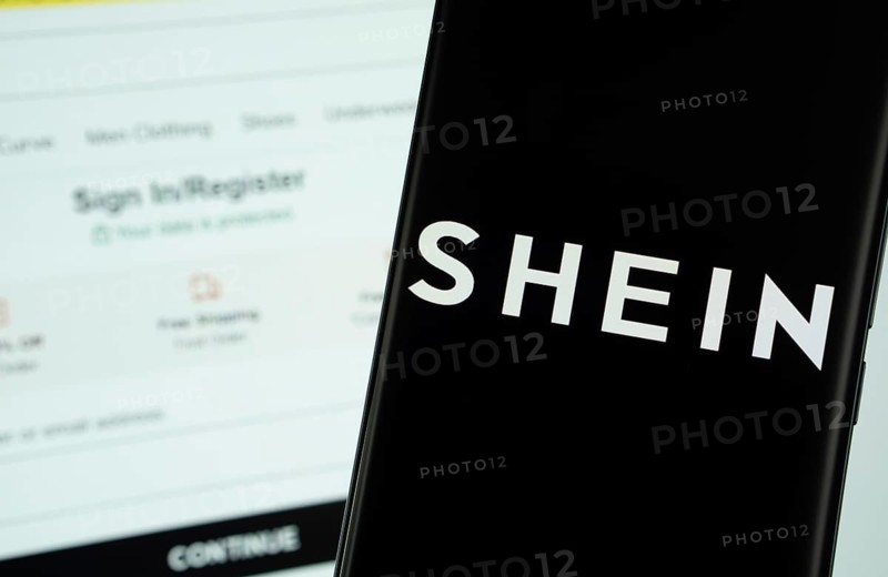Dhaka, Bangladesh - 18 March 2025: The logo of the shein is displayed on a smartphone screen, and the website shein is visible on a computer screen in the background