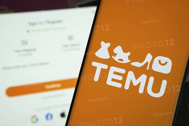 Dhaka, Bangladesh- 18 March 2025: Temu logo is displayed on a smartphone screen, with the temu login page visible on a computer screen in the background
