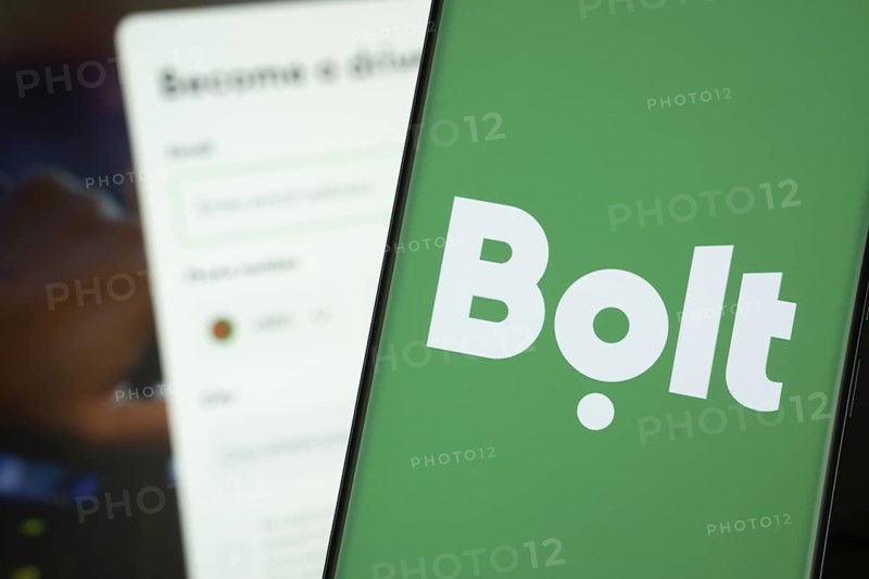Bolt logo is displayed on a smartphone screen, with the bolt website visible on a computer screen in the background