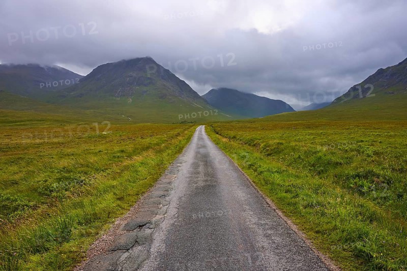 Endless straight road through vast grassland, framed by mountains under a cloudy sky, Glen Etive, Scotland, United Kingdom, Great Britain