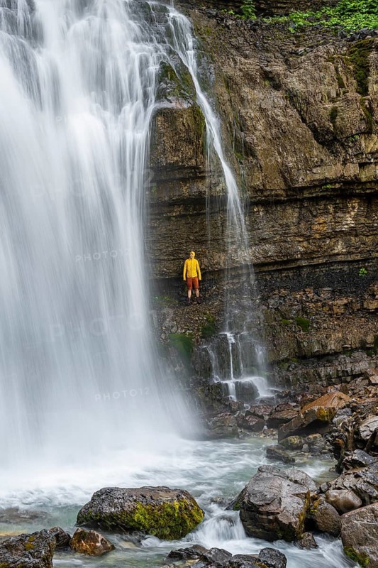 Adventure, Little hiker under large Cascata di Mezzo waterfall, long exposure, Vallesinella, Brenta, Trentino, Italy