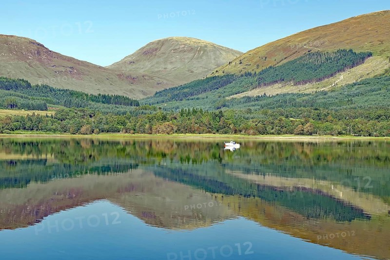 A quiet spur of an estuary with reflections of surrounding mountains and forests on a clear day, Highlands, Fort William, Scotland, Great Britain