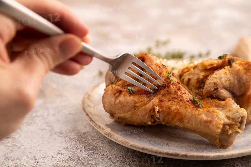 Fried Turkey Wing with spices and rice with hand on brown concrete background and linen textile. side view, close up, selective focus