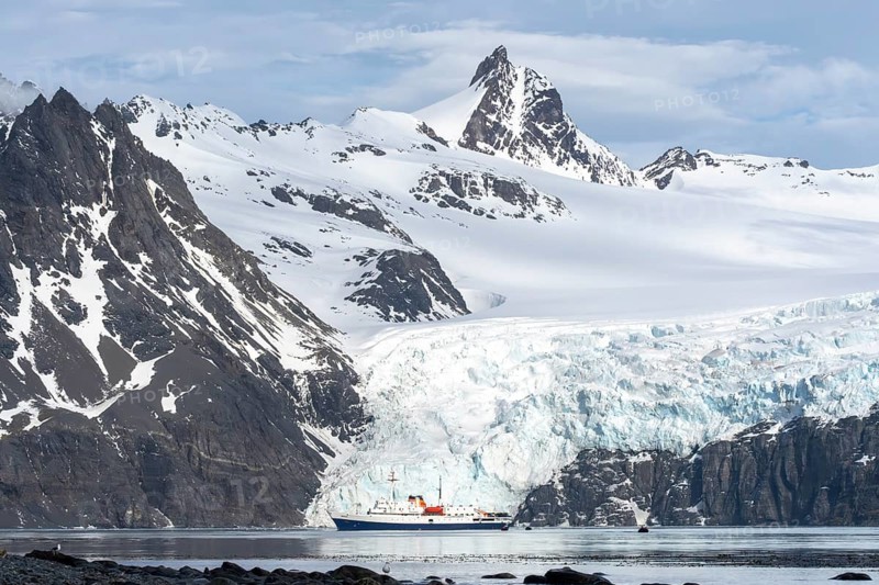 Expedition ship off glacier front surrounded by snow-capped mountains, Drygalski Fjord, South Georgia