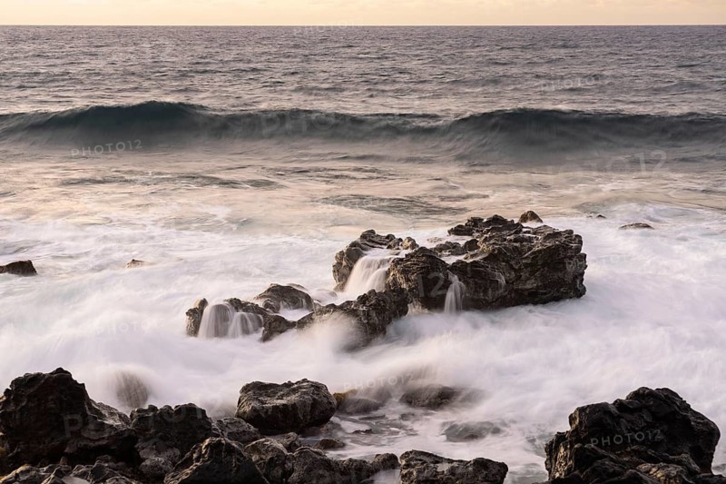 Surf with waves crashing over black lava rocks on the coast, Pacific Ocean at dusk, Easter Island (Rapa Nui), Chile