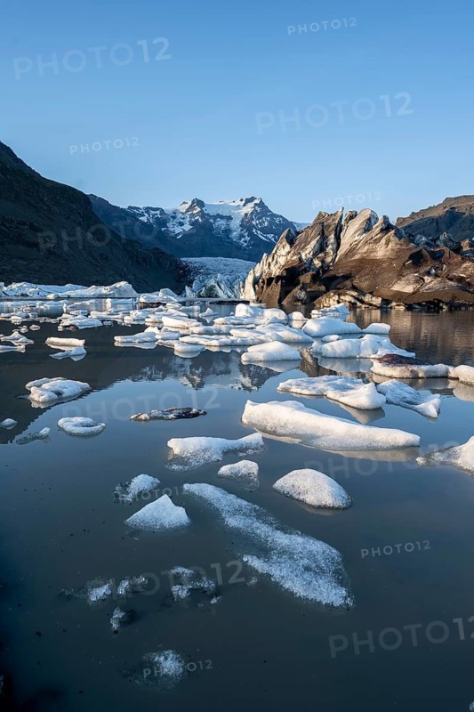 Reflection in the Svínafellslon glacier lagoon with ice floes, Svínasfellsjökull glacier tongue, glaciated mountain peak Hrútfjallstindar in the background, at sunset, Svínafell, Iceland