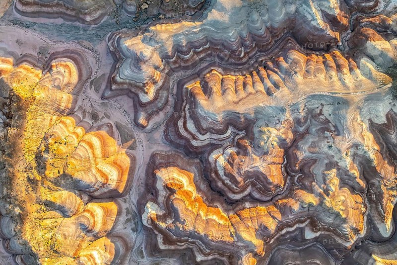 Aerial view of striking golden bentonite formations in Utah, USA. The layered textures and vibrant hues reveal geological wonders in this desert landscape