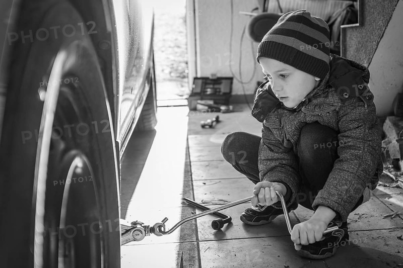Six years old boy changing the wheel in the car using jack