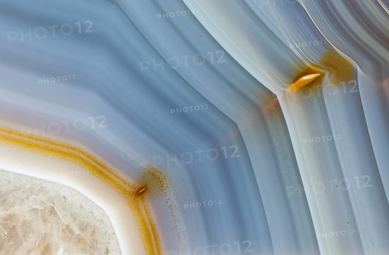 Detailed macro image of a Brazilian agate, highlighting its characteristic smooth banding in soft blue tones with golden inclusions and intricate natural formations