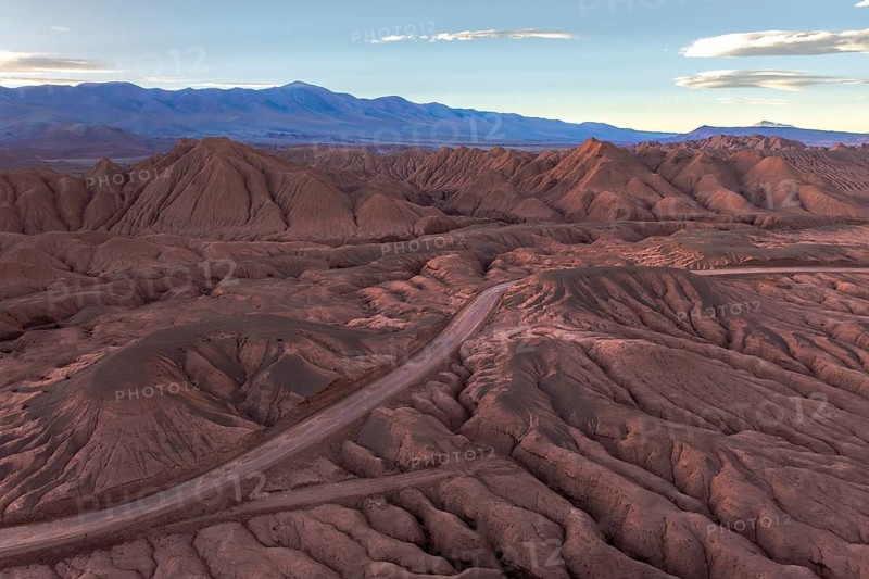 An aerial view of a rugged desert mountain landscape at sunrise, showcasing intricate patterns and hues under the soft morning light in the argentine Puna. Captivating natural beauty