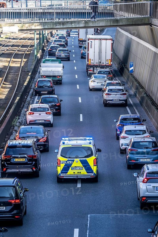 Traffic jam on the A40 motorway, emergency lane, vehicles on the left and right, police patrol car with flashing blue lights and siren, Essen, North Rhine-Westphalia, Germany