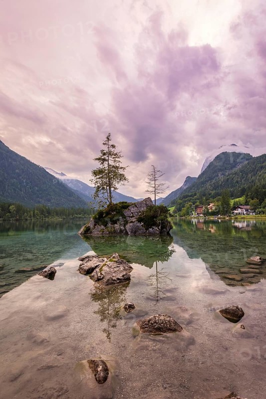 Hintersee with rocks and trees in the foreground, surrounded by mountains after sunset with dramatic cloudy sky, Ramsau, Berchtesgaden National Park, Berchtesgadener Land, Upper Bavaria, Bavaria, Germany