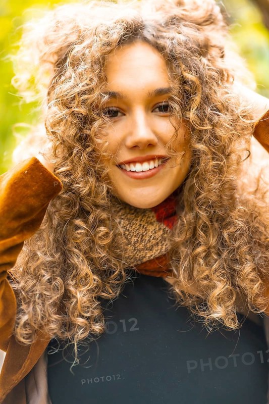 Close-up of a beauty woman with curly hair outdoors in a park with golden colors in the leaves