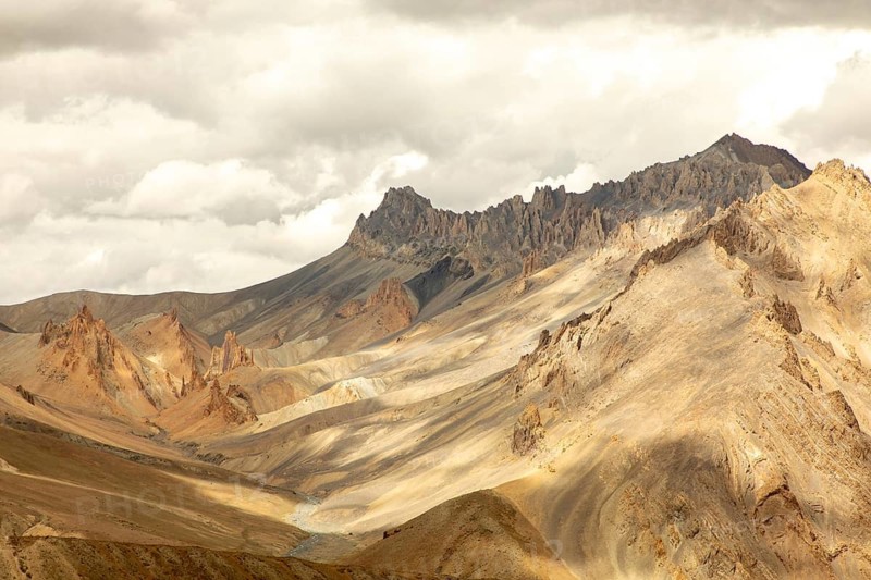 A stunning view of the rugged mountains in Zanskar Valley, Ladakh, India, showcasing the dramatic landscape with its unique rock formations under a cloudy sky