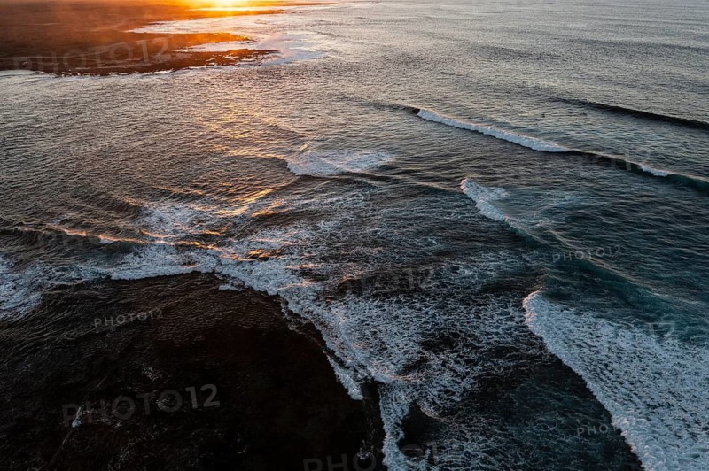 Stunning aerial shot capturing the golden sunset over the waves and rocky landscape of Popcorn Beach, Fuerteventura
