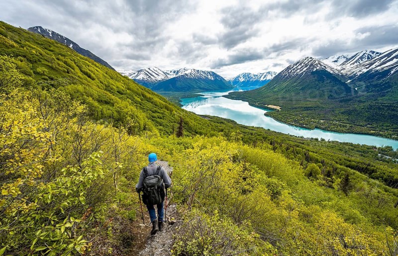 Climbers on a hiking trail, Slaughter Ridge Trail, view of snowy mountains in spring and turquoise blue Kenai Lake Lake, Cooper Landing, Kenai Peninsula, Alaska, USA