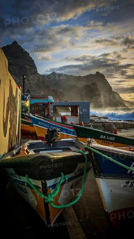 Colorful fishing boats on the shore with ropes and setting sun over the sea, dramatic coastal scenery, mountains in the background, romantic harbor scene in the evening light, Ponta do Sol, Santo Antao, Cabo Verde, Cape Verde, Cape Verde