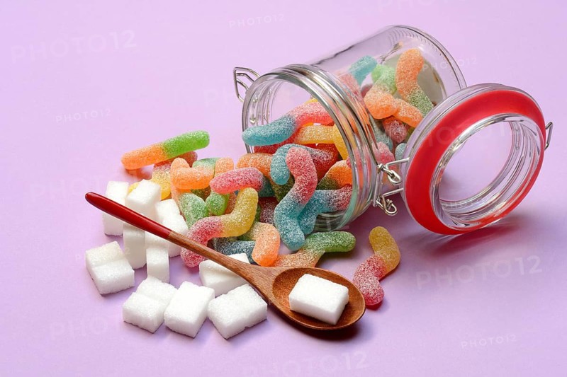 Lots of colorful jelly sweets in glass containers and sugar cubes, sugar consumption