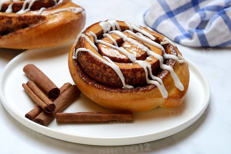 Cinnamon roll on plate and cinnamon sticks