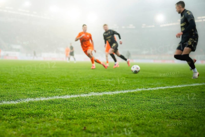 Grass and sideline on the football pitch at the stadium and player's legs at the background in Lubin, Poland